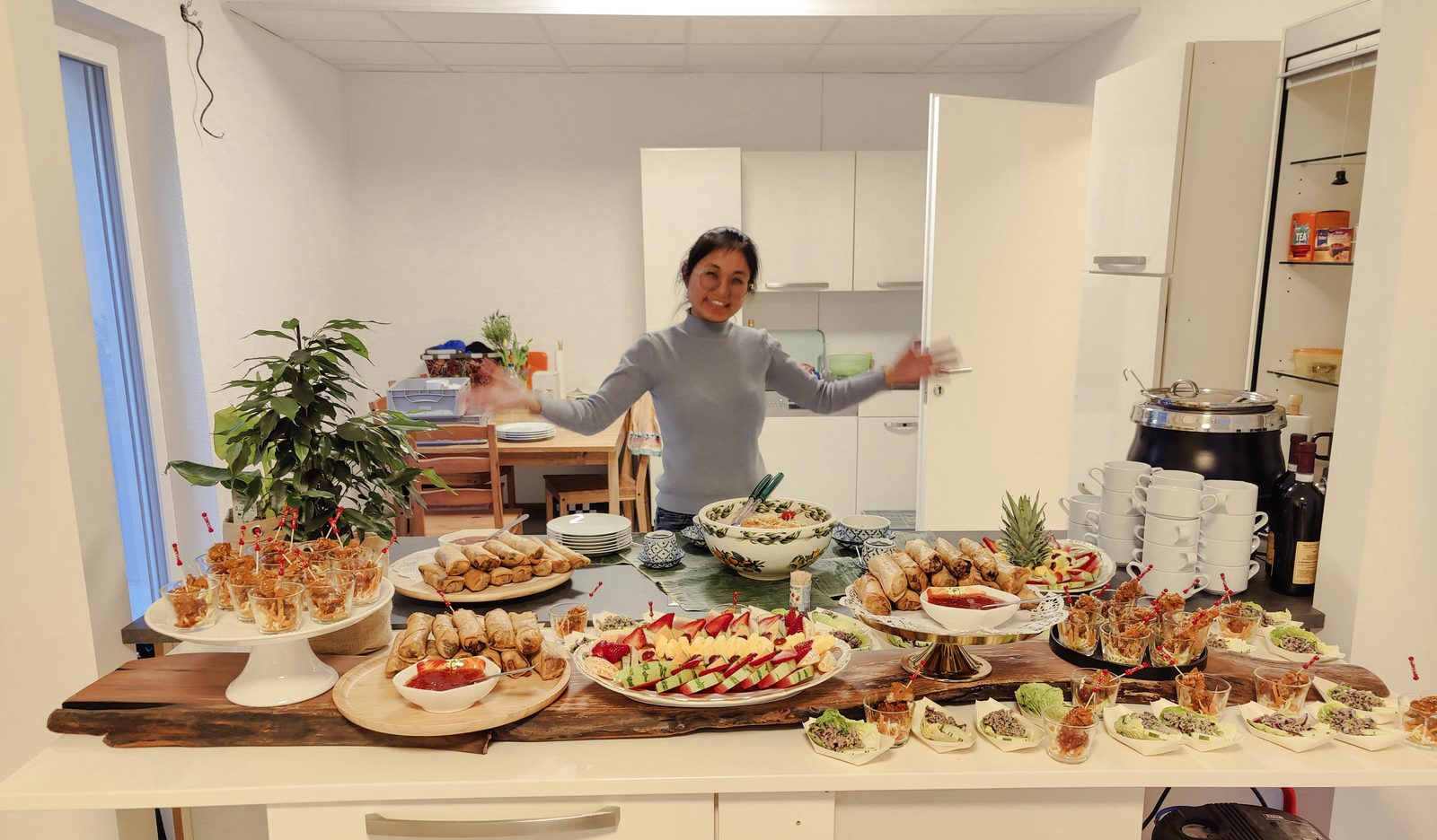 Pearl vor einem fertig aufgebauten Catering-Buffet mit Fingerfood, Frühlingsrollen und Obstplatte