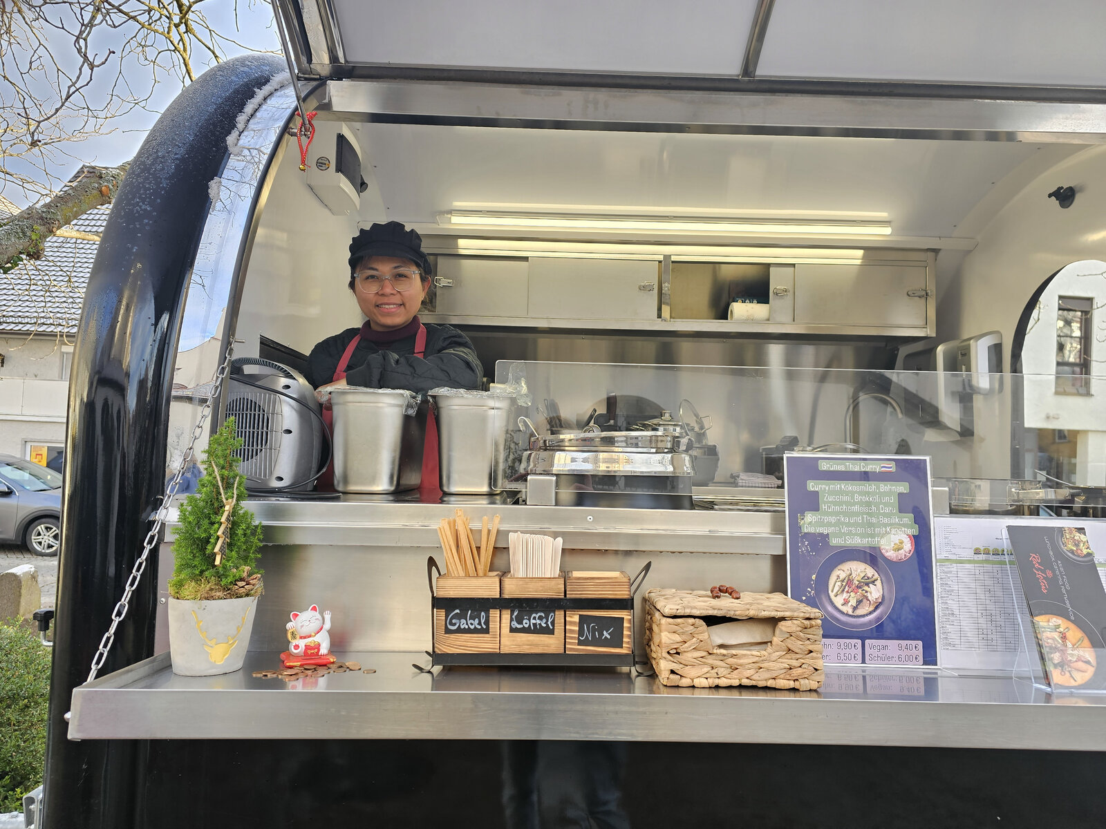 Pearl im Foodtruck-Fenster bei der Zubereitung von Grünem Thai Curry