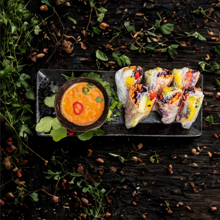Vietnamesische Sommerrollen mit Hoisin-Erdnussdip auf dunkler Platte